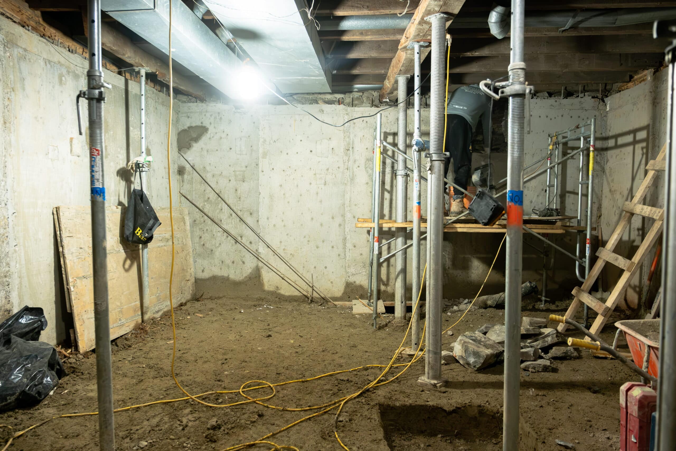 basement-underpinning-toronto-basement-lowering-willfix Basement lowering in progress with adjustable steel support columns and scaffolding holding floor joists during underpinning excavation