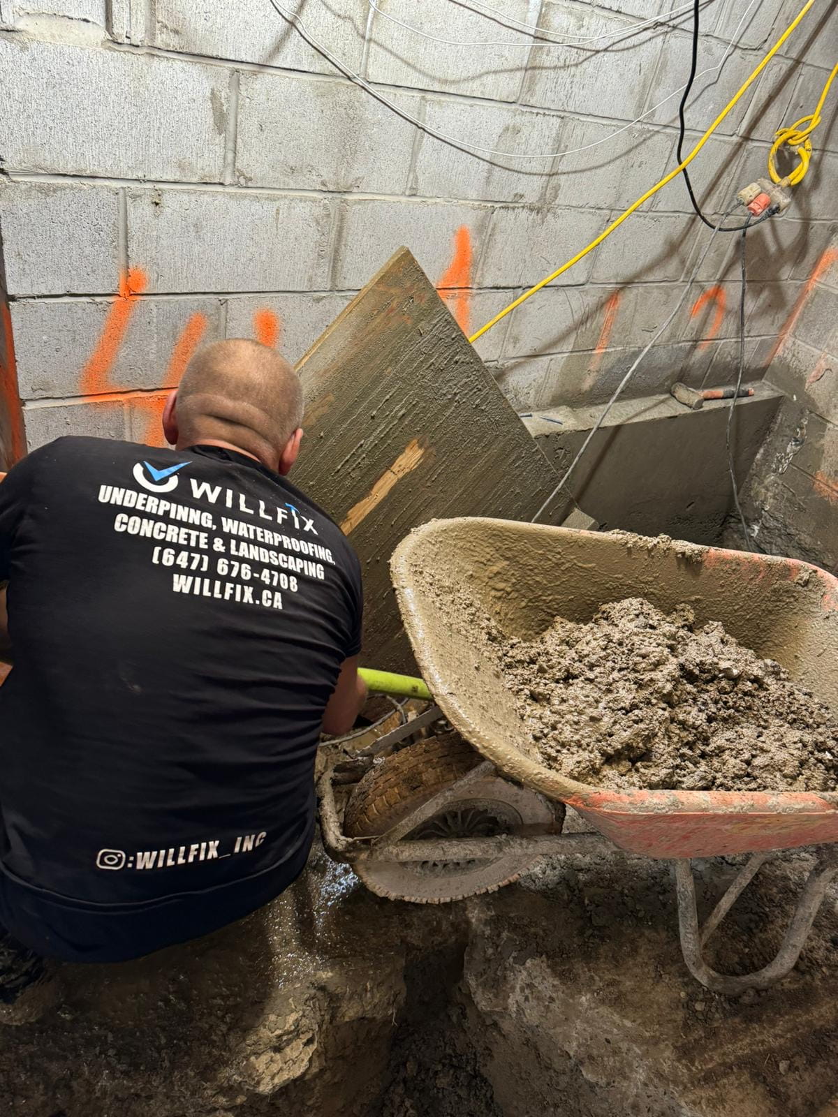 basement-underpinning-toronto-bench-footing-willfix WillFix worker pouring concrete for bench footing during basement underpinning in Toronto