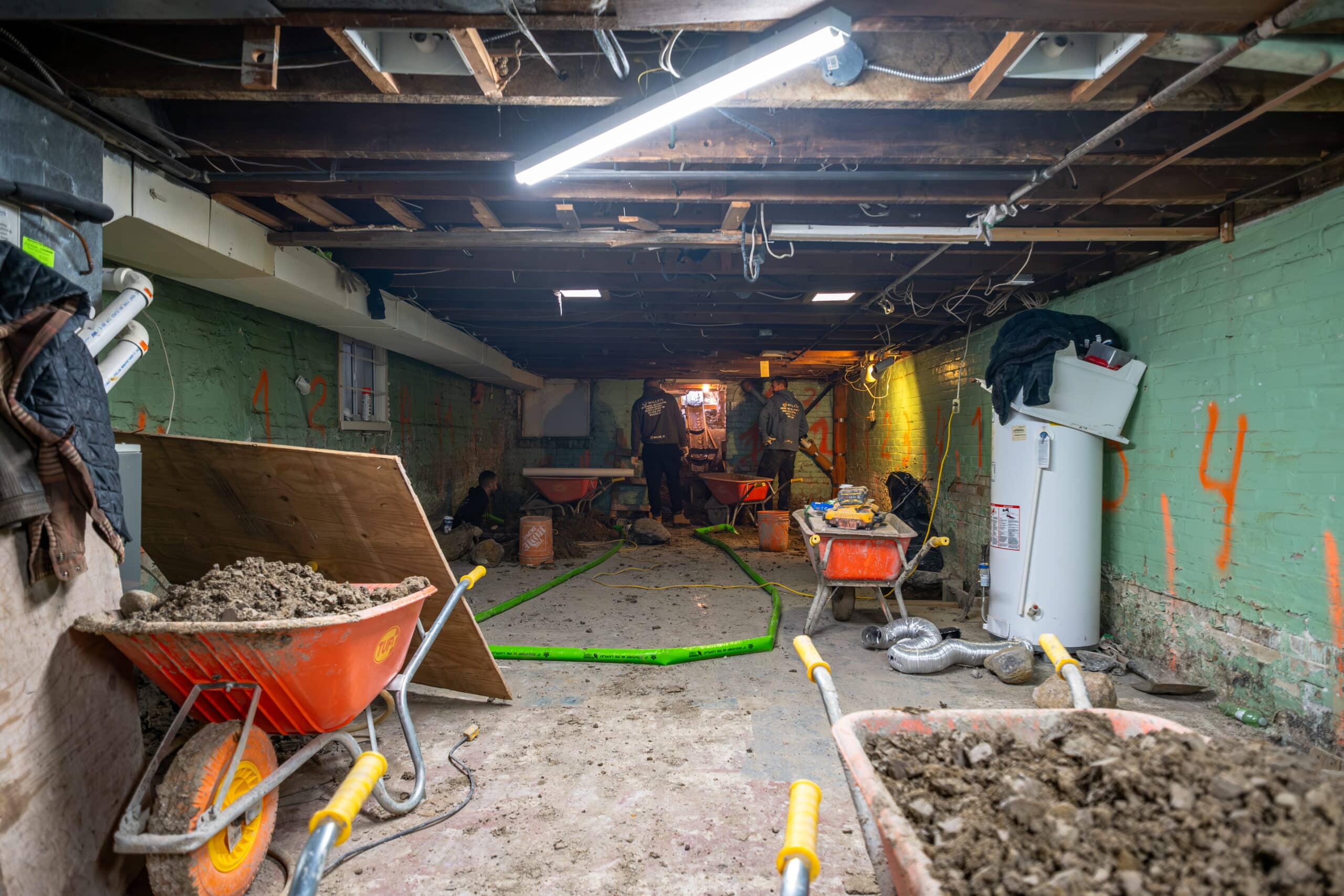 basement-underpinning-toronto-crawl-space-excavation-willfix Crew excavating basement crawl space with multiple wheelbarrows and equipment during underpinning project in Toronto