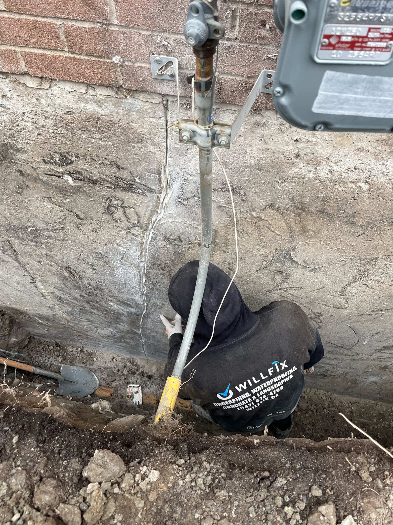basement-underpinning-toronto-foundation-crack-repair-willfix WillFix technician repairing vertical crack in exterior concrete foundation wall during excavation