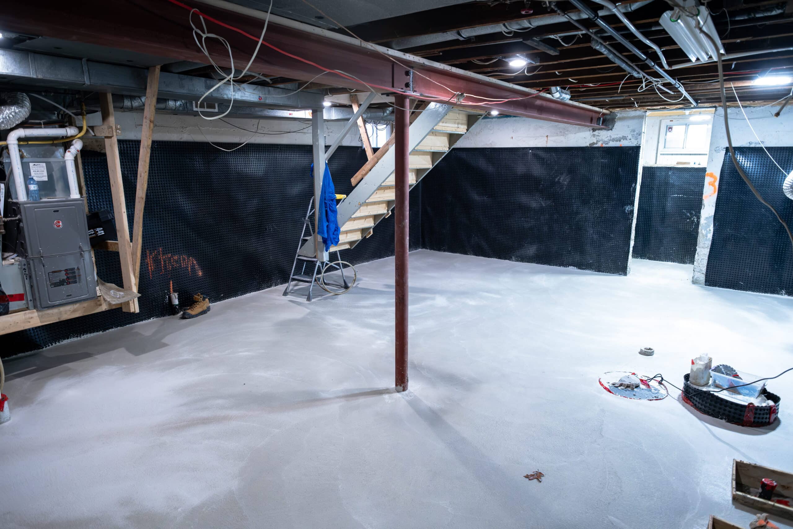basement-underpinning-toronto-load-bearing-wall-removal-willfix Lowered basement after load-bearing wall removal with steel beam, support column, dimple mat walls and new concrete floor