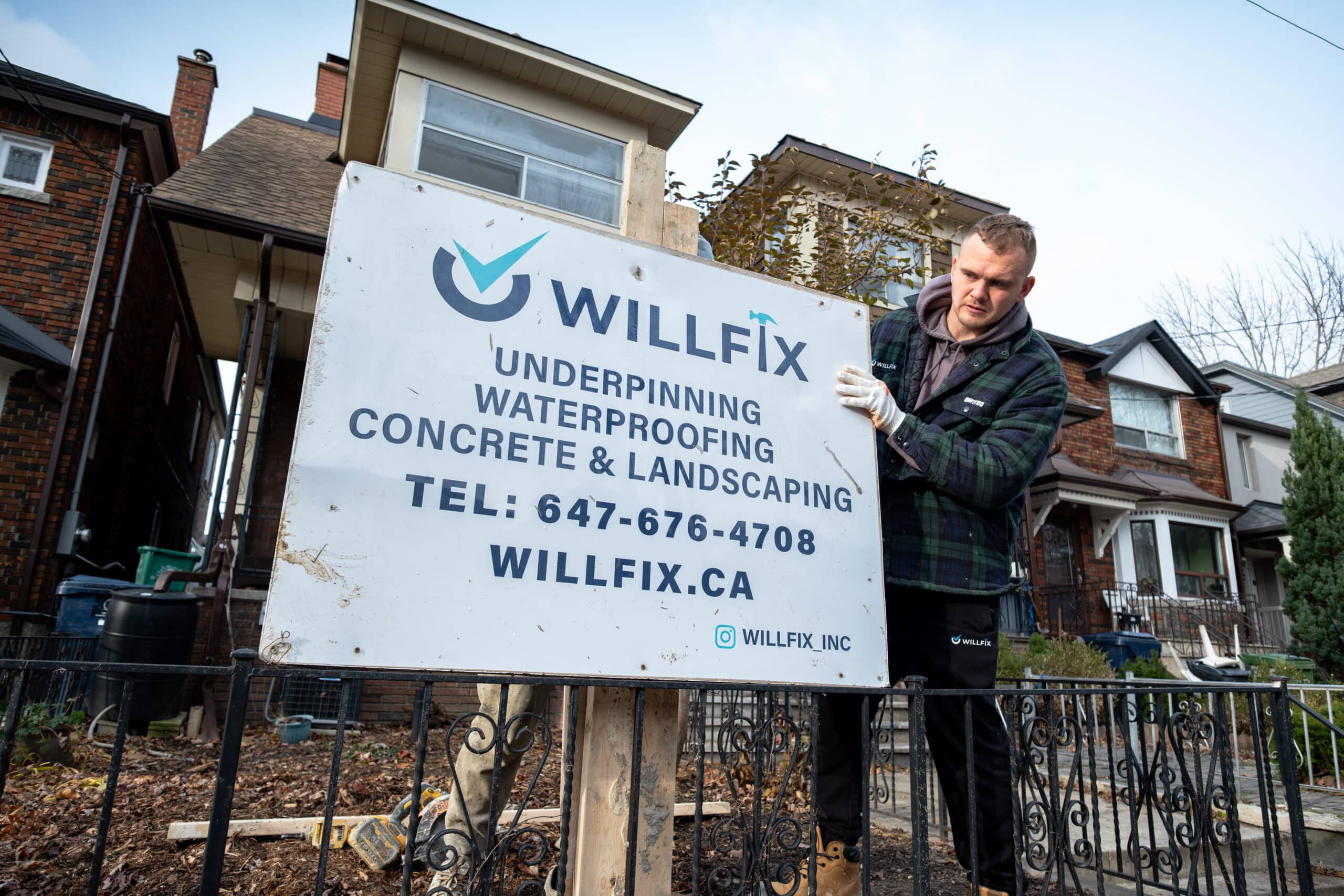 WillFix contractor setting up a job site sign for basement underpinning and waterproofing services in Toronto