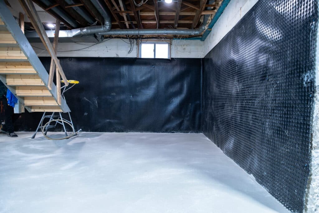 Basement interior with dimple mat waterproofing membrane installed on walls and freshly poured concrete floor