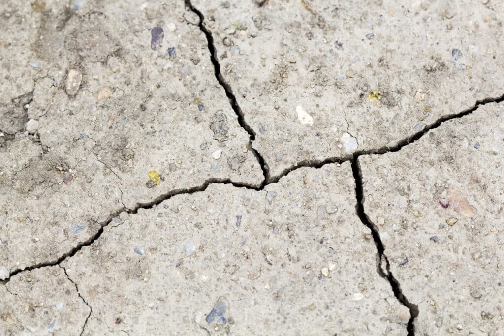 Close-up of cracks in a concrete basement wall — common sign of foundation damage requiring underpinning or waterproofing repair