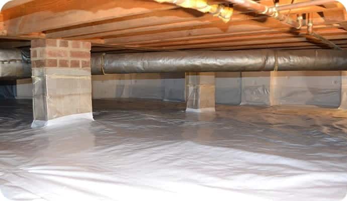 Encapsulated crawl space with vapor barrier covering ground and brick support columns under home floor joists