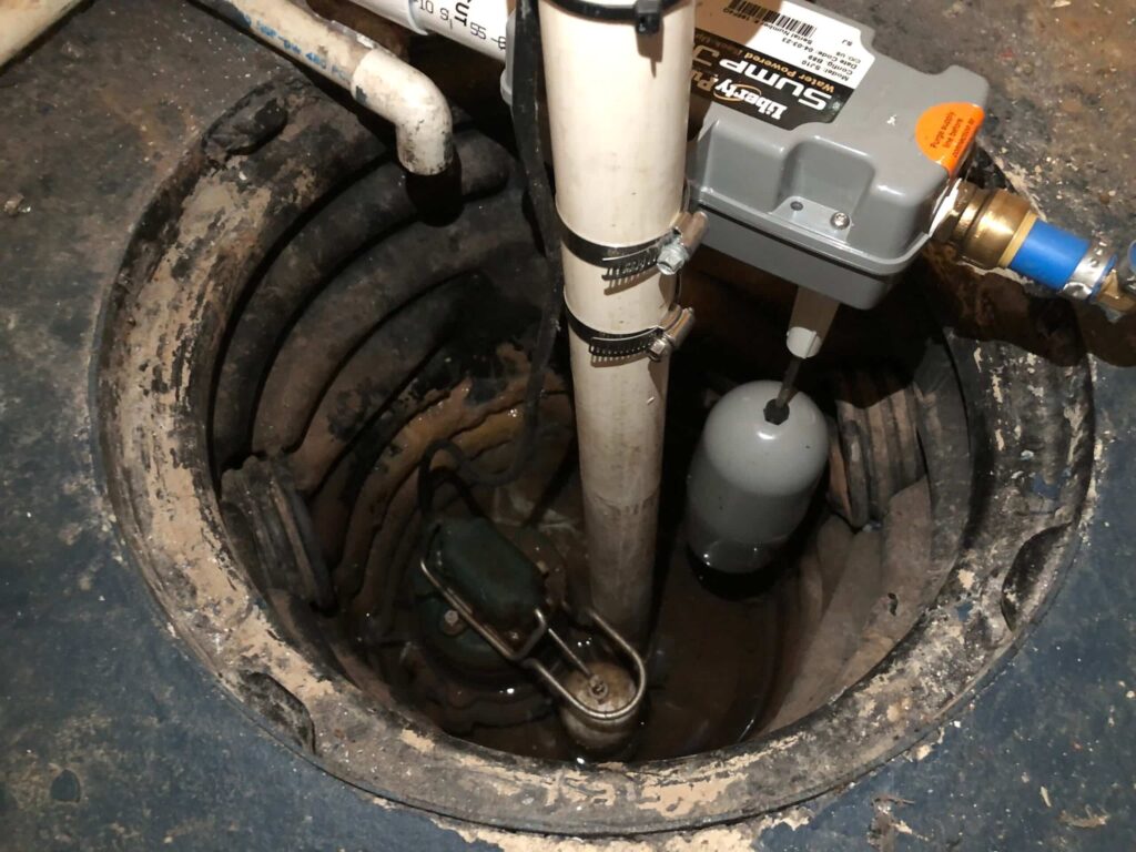 Liberty sump pump installed in basement pit with discharge pipe, float switch and check valve for basement water removal